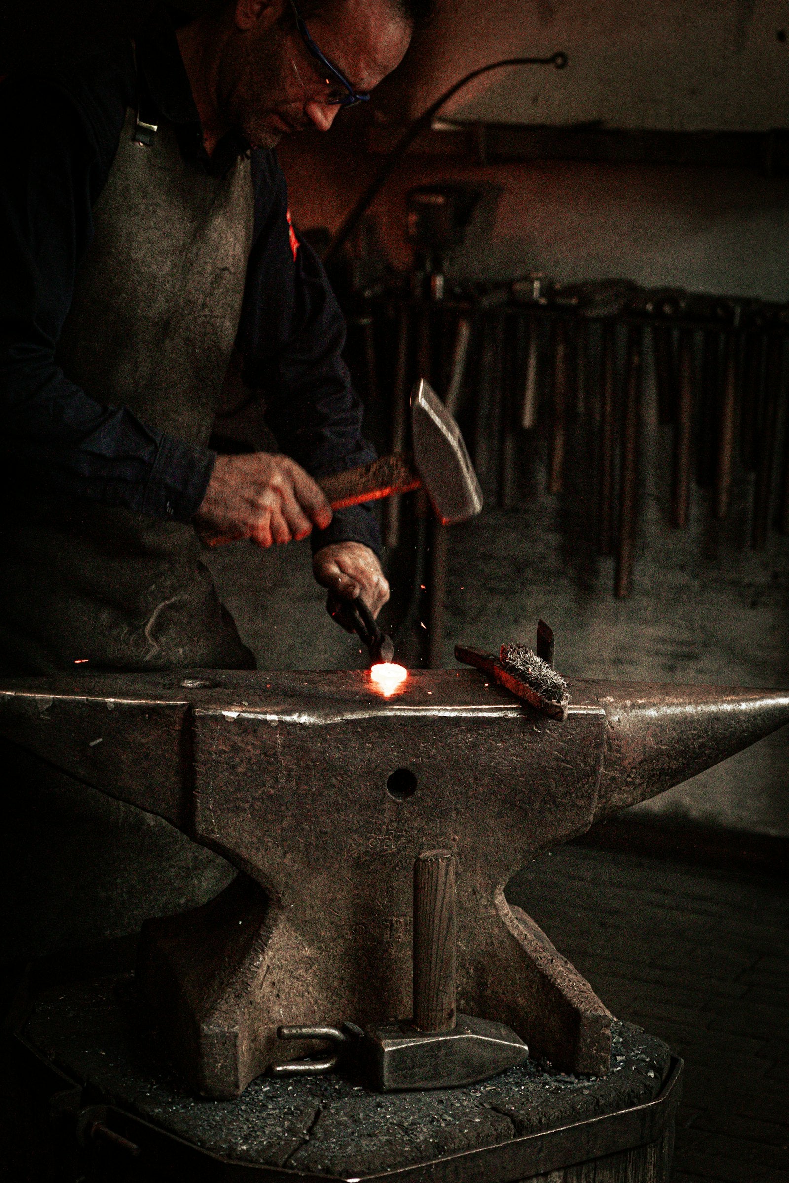 Blacksmith working on a piece of metal with a hammer at the anvil